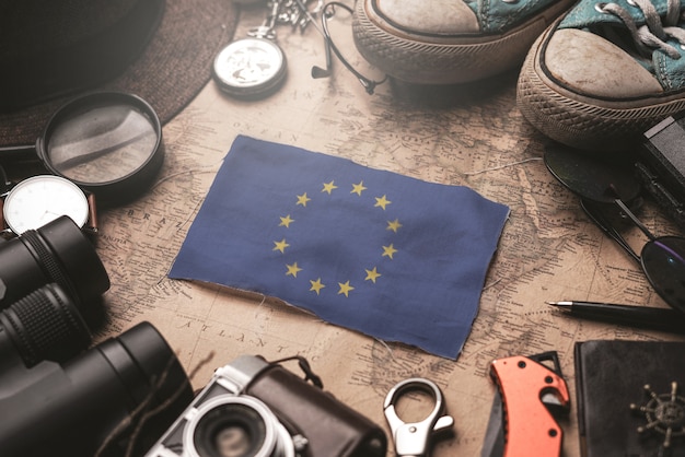 European flag between traveler's accessories on old vintage map. tourist destination concept.