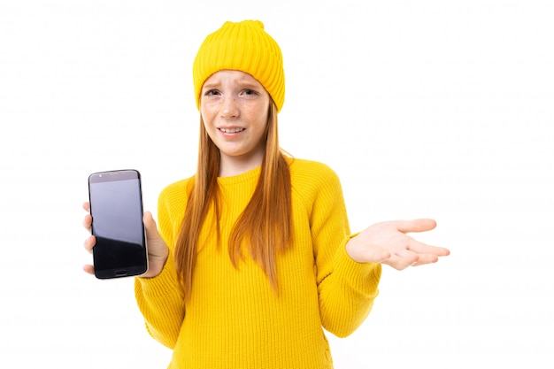 European girl shows a phone screen on a white studio 