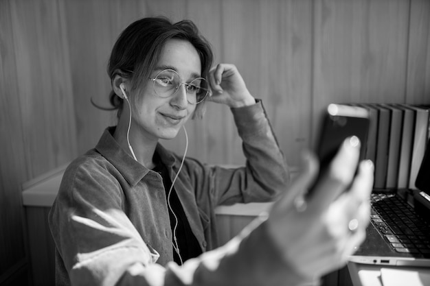 European girl using a mobile phone communicates with friends in an online chatblack and white photo