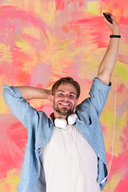 European guy have fun time cheerful teenage dj listening songs\
via earphones blue eyed stylish hipster with smartphone musical\
lifestyle american handsome bearded guy with headphones