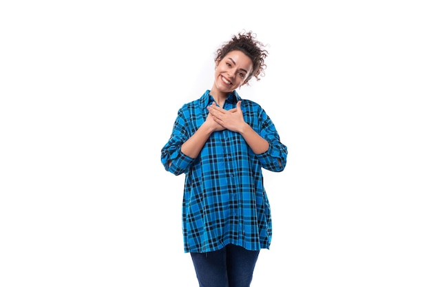 Foto una gentile giovane donna europea con i capelli ricci a coda di cavallo vestita di camicia blu.