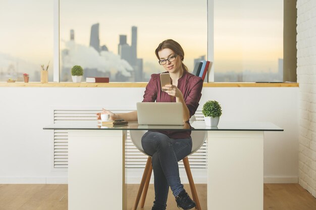 European lady using smartphone and notebook