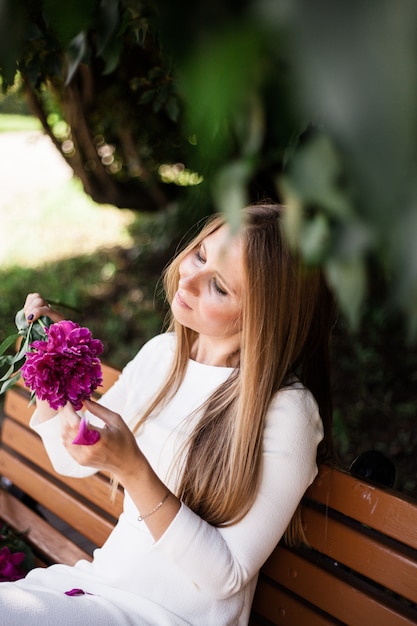 Ragazza dall'aspetto europeo con fiori, peonie nelle sue mani