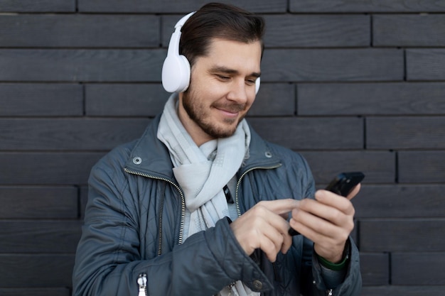 European male freelancer listening to music on headphones in app on phone