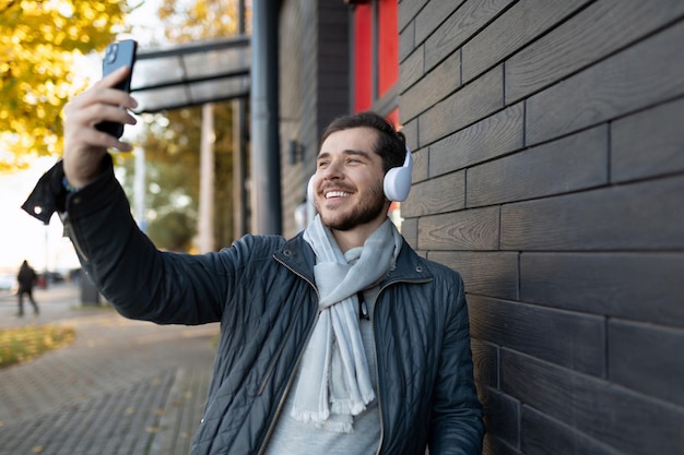 European male freelancer taking selfie with headphones outdoors
