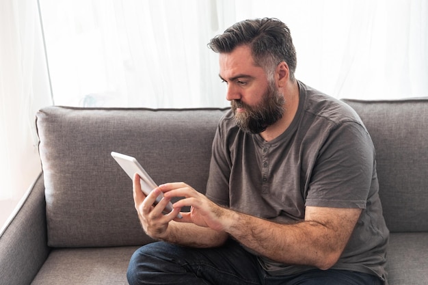 European man with a beard looks at a tablet