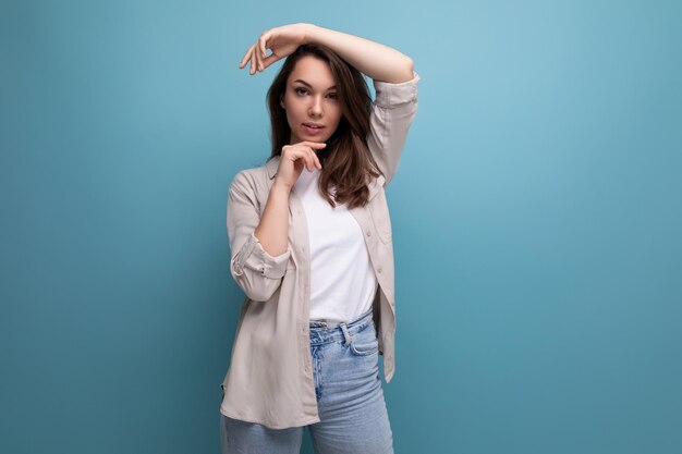 European model appearance young darkhaired lady in informal clothes posing against a blue background