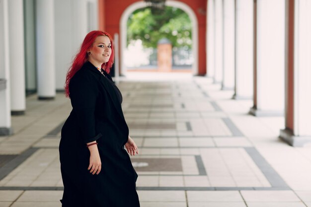 European plus size woman walking outdoor street city Young red pink haired body positive girl