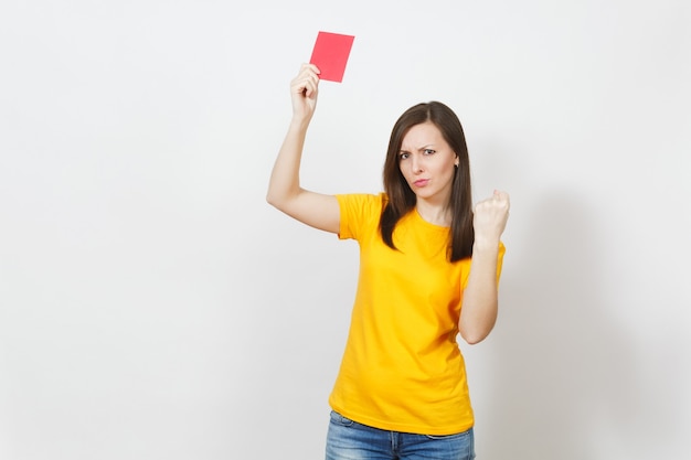 European serious severe young woman, football referee in yellow uniform show red soccer card, propose player retire from field isolated on white background. Sport, play, healthy lifestyle concept.