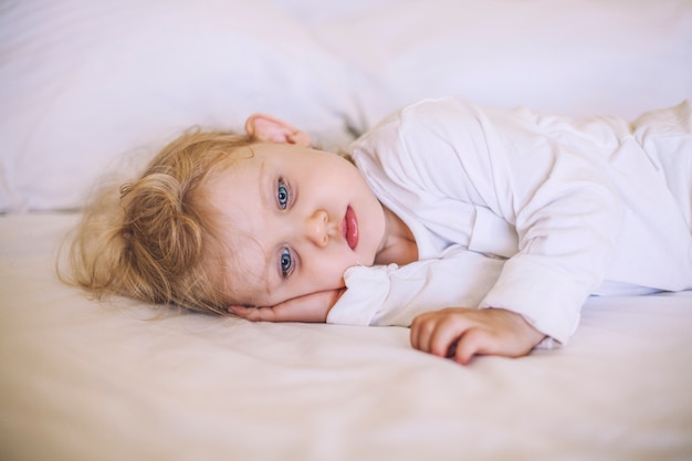 European small child lying on the bed. White, sad, beautiful, boy, girl