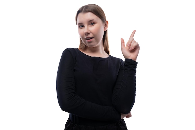 European smart schoolgirl dressed in a black blouse holds a thumbs up