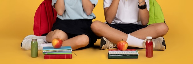 European teenager children with apples lunch boxes sit on floor eat food