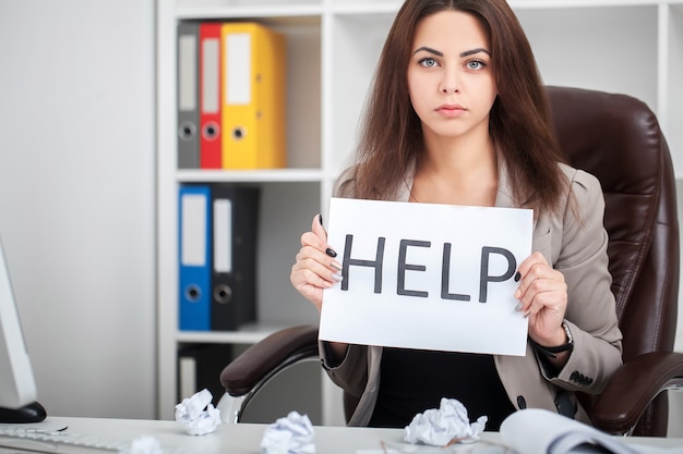 Европейская усталая и разочарованная женщина, работающая секретаршей в состоянии стресса на рабочем месте в офисе с письменным столом с просьбой о помощи в концепции разочарования