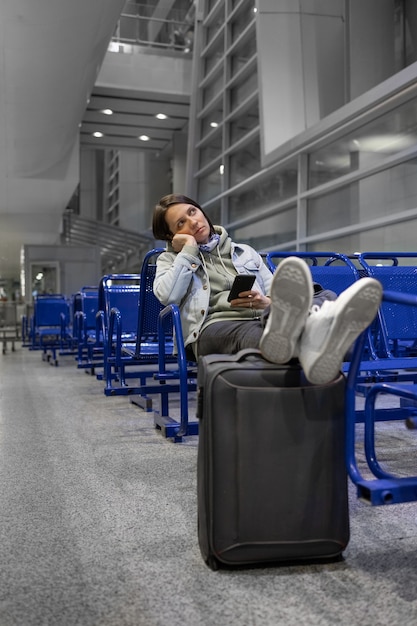 European woman at the airport waiting to board her flight flight and boarding delays