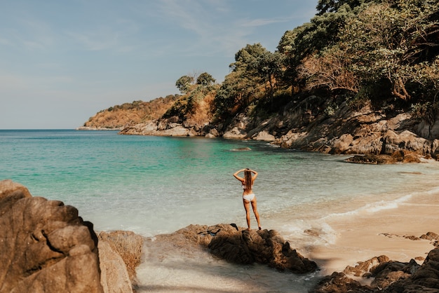 European woman in bikini swimsuit stands backwards