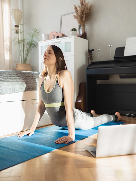 european woman on blue yoga mat meditating at home yoga stretches and breathing practices online