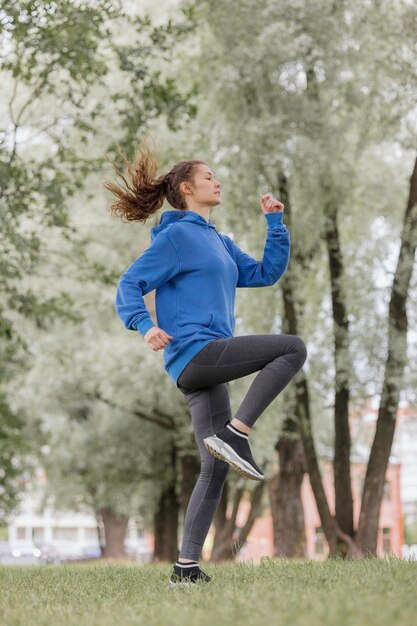 A European woman does sports in a park or a public place warmup and jogging in the fresh air