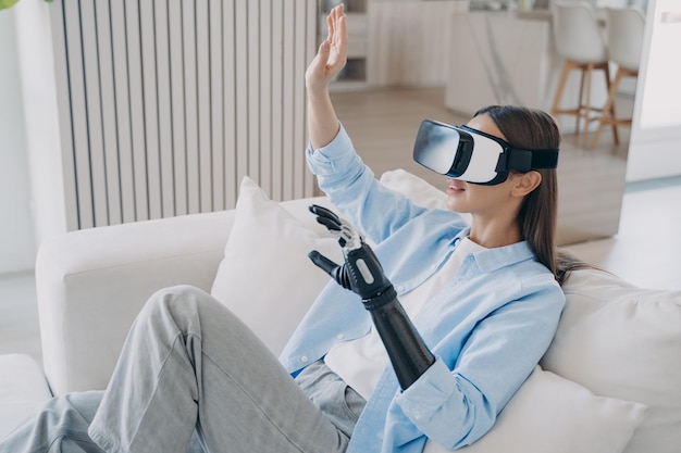 European woman is getting used to modern bionic prosthesis using vr headset Electronic technology