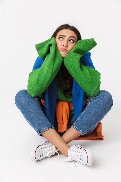 european woman with dark hair in colorful clothes sitting on the floor, isolated on white