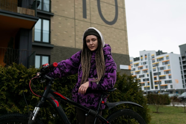 European woman with dreadlocks and piercing rides a bicycle