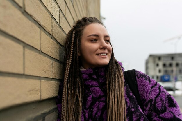 European woman with dreadlocks and piercings walks around the city on a day off