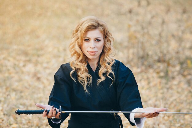 European woman with a katana in a kimono. the girl trains martial arts. a woman in the autumn forest. a warrior with a cold weapon in his hands