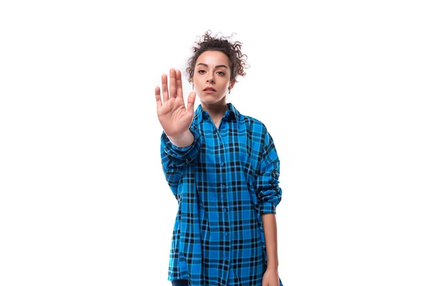 A european young lady with a curly ponytail hairstyle dressed in a blue shirt actively gesticulates