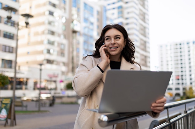 Designer europeo giovane donna con un computer portatile in mano sullo sfondo degli edifici stradali