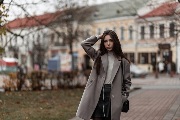 European young woman in a fashionable gray coat on a street in the city on an autumn day