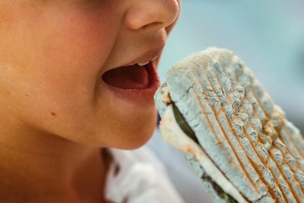 Подросток европейского внешнего вида кусает сэндвич рот крупным планом ест фаст-фуд закуску процесс еды