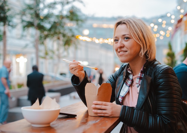 Europees blondemeisje die rijst Pho Bo met de houten Vietnamese koffie van de stokkenlijst eten straat in Moskou.