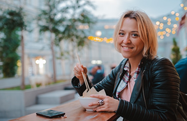 Europees blondemeisje die rijst Pho Bo met de houten Vietnamese koffie van de stokkenlijst eten straat in Moskou.