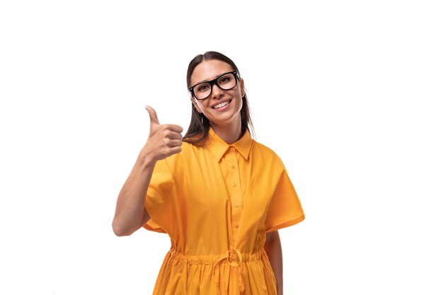 Europese jonge brunette dame met een oranje zomerjurk en bril.