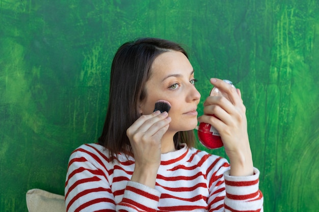 Europese vrouw doet make-up Kaukasische vrouw doet poeder op haar gezicht