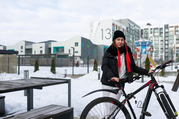 Europese vrouw in winterkleding die in de winter op een fiets rijdt