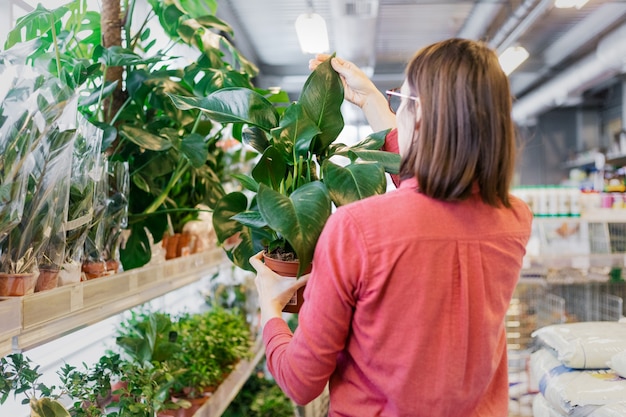 Europese vrouw met donker haar een rood shirt selecteert planten in een tuin hypermarkt vrouw tuinarchitect