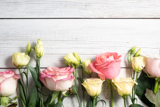 Photo eustoma flowers and pink roses on wooden background in vintage style. romantic wedding background.