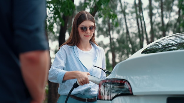 EV car recharging electricity for battery by lovey couple on road trip Exalt