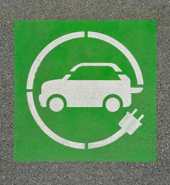 EV 電気自動車充電ステーションはアスファルトにサインします。アスファルトのテクスチャに「E」サインします。