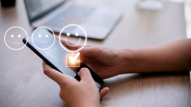 Foto evaluatieconcept van de klantenservice met behulp van een smartphone drukt op gezichtsemoticon die tevreden glimlacht op virtueel touchscreen