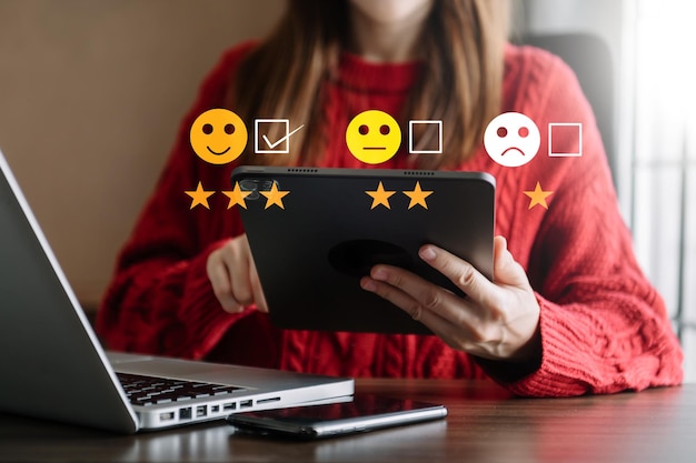 Evaluatieconcept van de klantenservice Zakenvrouw die op een emoticon met een glimlach op het gezicht drukt, wordt weergegeven op het virtuele scherm op tablet en smartphone in officexA
