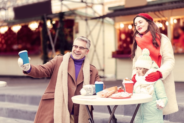 Even kijken. Emotioneel meisje dat aan de tafel staat en gebak met cacao eet