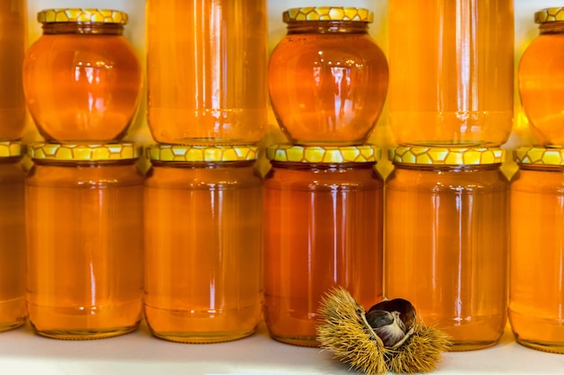 生の栗で飾られた透明なガラスの瓶に黄色い蓋が付いた栗の蜂蜜が入った缶の列でさえ。セレクティブフォーカス