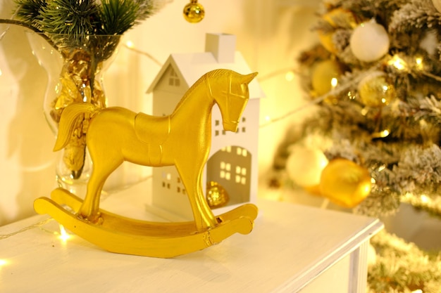 Evening Christmas atmosphere A golden toy horse stands on the background of a Christmas tree