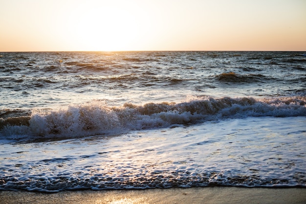 夕方の暗い海の青い波日没の砂浜海の泡の柔らかい波