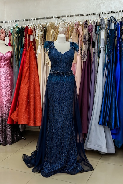 Photo evening dresses hang on a shelf in store