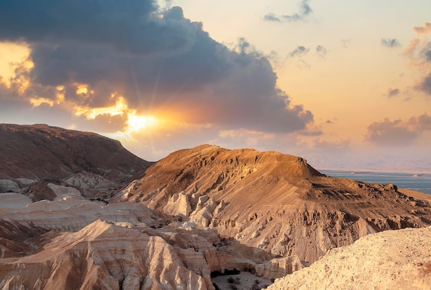 Evening gold sunset sky over mountain Sodom Gomorrah from Negev desert Israel Dead sea Sunset on a large salt formation mountains range Sodom with fluffy clouds Sun shining on rocky landscape