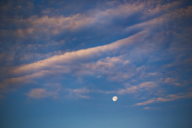 Evening moon on the blue sky with clouds, evening cloudscape