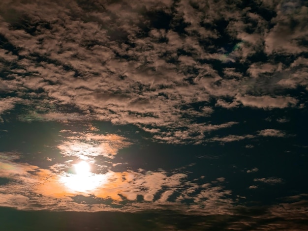 青い空に白い雲の後ろに夕方のオレンジ色の日当たりの良い夕日