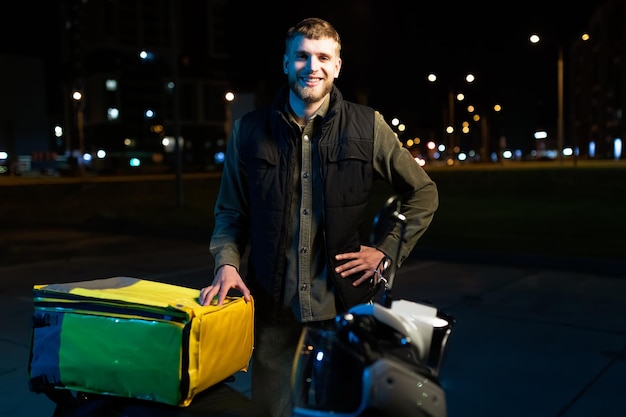 Evening portrait of a male courier on a scooter Roundtheclock food delivery